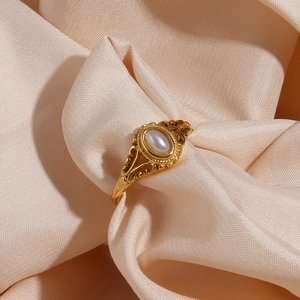 Close-up of vintage gold floral ring with oval pearl on champagne satin background