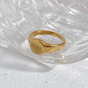 Chevalière plaquée or 18 carats avec gravure fuck sur un fond texturé blanc