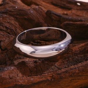 Macro shot of polished silver stainless steel ring on a textured wood background