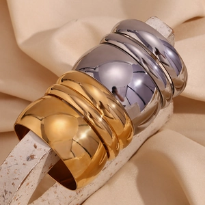 Set of six chunky mirror-polished gold and silver stainless steel bangles on stone