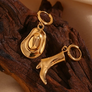 Macro detail of 18K gold plated cowboy hat and boot charms on stainless steel earrings