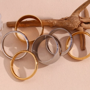 Close-up of minimalist gold and silver polished stainless steel bracelets on a textured base