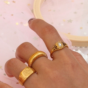 Detail of vintage gold-plated rings with freshwater pearl and engraved slogan text