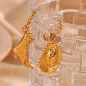 Detailed close-up of 18K gold cowboy boot and hat charms hanging on a glass rim