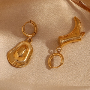 Macro shot of asymmetrical 18K gold plated cowboy hat and boot charms on hoop earrings