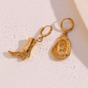 Macro detail of 18K gold plated cowboy boot and hat earrings with polished metal texture