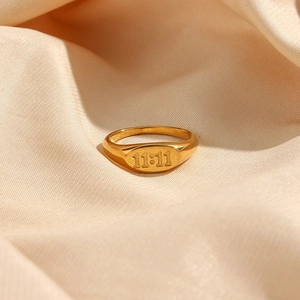Macro shot of 18K gold plated oval signet ring featuring 11:11 engraving on satin fabric
