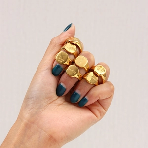 Primer plano de anillos de sello chapados en oro con citas inspiradoras grabadas en la mano
