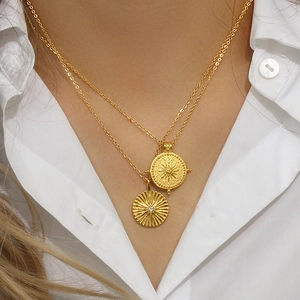 Vue macro détaillée de pendentifs superposés boussole solaire plaqués or 18K avec zircone