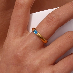 Dettaglio dell'anello in acciaio inossidabile dorato con zircone blu rettangolare incassato