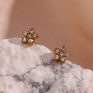 Macro shot of 18K gold plated flower earrings with micro-set zircon on white stone
