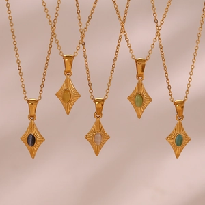 Detalle de los colgantes de rombo con piedra de ojo de gato y textura solar en cadenas de oro