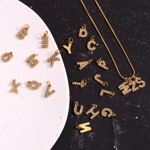 Macro detail of gold 18K plated alphabet pendants with rhinestones on a snake chain