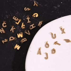 Macro view of tiny 18K gold plated letter pendants with micro-pave white zircons