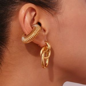 Makroaufnahme von vergoldetem spiralförmigem Earcuff und ovalen Gliederketten-Ohrringen