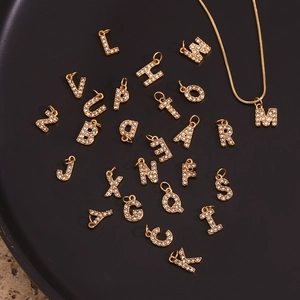 Close-up of 18K gold plated alphabet pendants with sparkling rhinestones on black tray