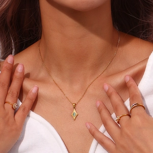 Primer plano del collar dorado con colgante de ojo de gato y anillos de oro en la modelo