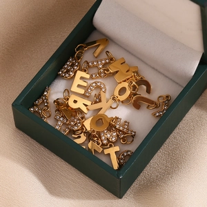 Macro detail of 18K gold plated A-Z letter charms with rhinestones on green silk
