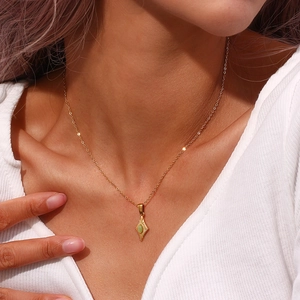 Primer plano del collar dorado con colgante de corazón ojo de gato y suéter blanco