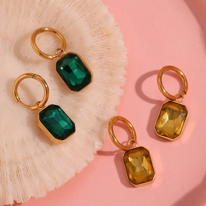 Macro shot of gold-plated hoop earrings with green and amber rectangular zircon crystals