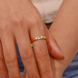 Dettaglio anello placcato oro 18 carati con zircone blu sulla mano di una donna