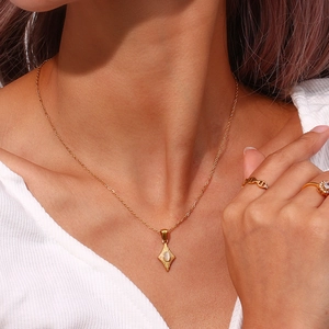 Detalle de collar dorado con colgante de rombo y piedra ojo de gato sobre punto acanalado