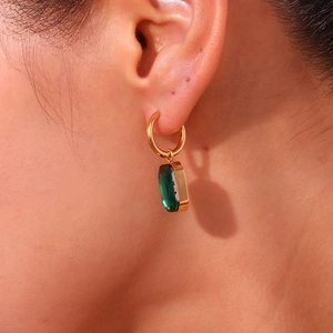 Detail of 18K gold plated earring with rectangular green zircon on female ear model