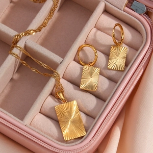 Detail of 18K gold plated jewelry set with sunburst engraved rectangular pendants