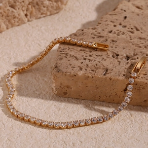 Detailaufnahme eines 18K vergoldeten Tennisarmbands mit Zirkonia auf Steinuntergrund