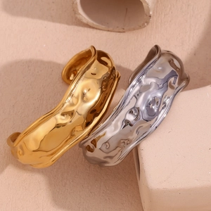 Detail of 18K gold and silver open bangles with hammered texture on a stone background