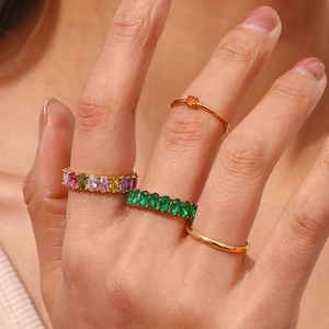 Close-up of a stacked gold ring set featuring oval emerald and colorful zircon stones