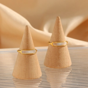 Détails de deux bagues minimalistes dorées avec incrustation de nacre sur supports bois