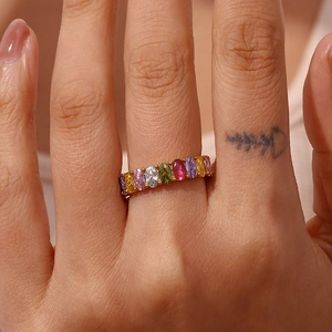 Detailed macro view of gold-plated oval multi-color rainbow gemstone ring on finger