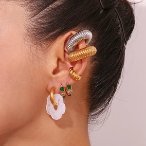 Detail of layered gold floral drop earring with white resin petals and green zircon accent