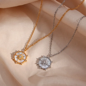 Détails de colliers roue en or et argent avec nacre sur fond de soie champagne