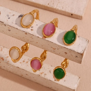 Detailsicht auf goldene Armreifen mit rosa, weißen und grünen Katzenaugen-Steinen