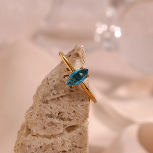 Detail eines 18K vergoldeten Rings mit blauem Zirkon im Marquise-Schliff auf Stein