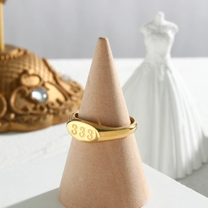 Polished 18K gold stainless steel signet ring with oval engraved 333 on wooden stand