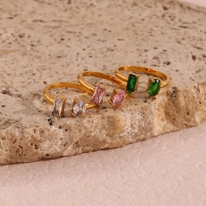Vue détaillée de trois bagues dorées ajustables avec zircons de couleurs sur pierre brute