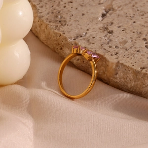 Gros plan d'une bague dorée ornée de trois zircons roses sur une pierre élégante