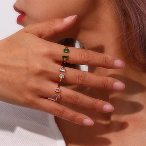 Gros plan de bagues dorées ajustables avec zircons rectangulaires roses et verts