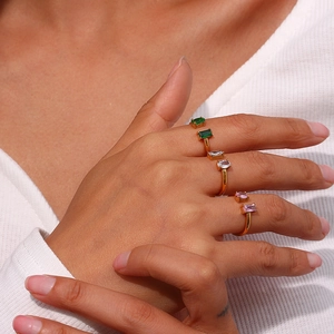 Détail de trois bagues dorées ornées de zircons verts, blancs et roses sertis