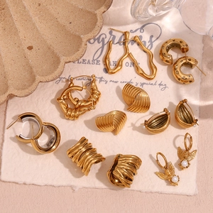 Macro view of assorted 18K gold plated stainless steel geometric earrings on beige fabric
