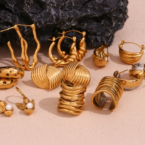 Detailed collection of 18K gold plated multi-layer geometric earrings on dark stone