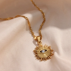 Macro detail of gold evil eye sunburst pendant with zircon on beige silk fabric