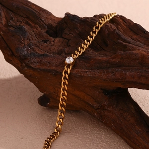Detail eines 18K vergoldeten Kettenarmbands mit Zirkonia auf rustikalem Holz