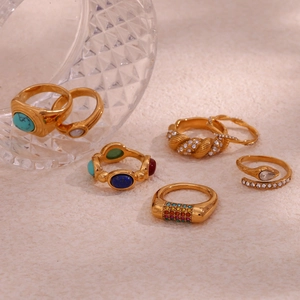 Detail of 18K gold plated rings set with turquoise and lapis stones on warm sand background