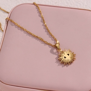 Macro detail of gold evil eye sunburst pendant necklace on a pink jewelry organizer box