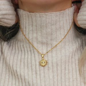 Detail of evil eye sunburst pendant with zircon on a wavy water ripple chain