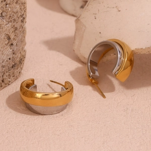 Detail of two-tone C-shape hoop earrings in polished 18K gold and silver finish